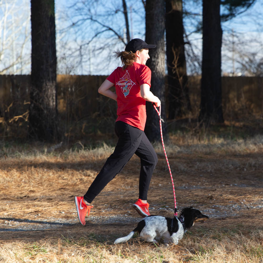 Woman running with her dog on a training leash