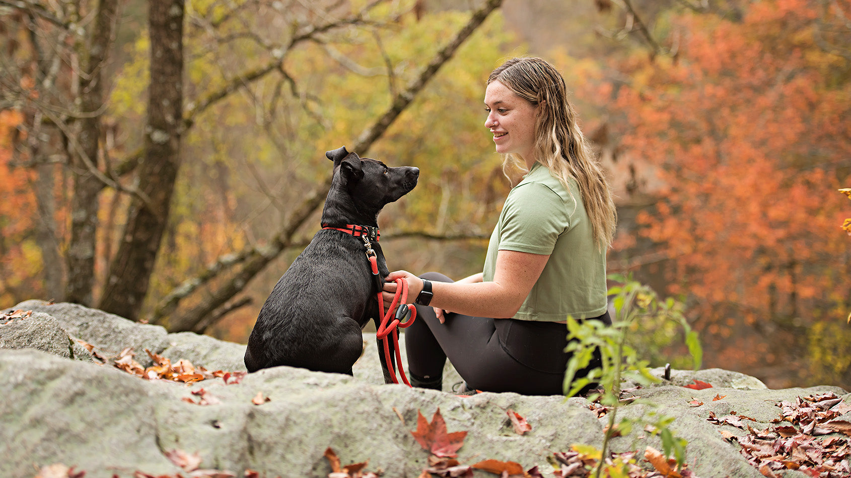 Woman with black dog that has red Rope Hounds dog leash and collar.