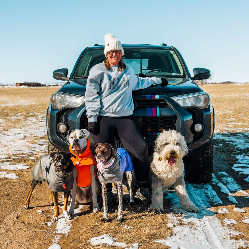 Woman standing in front of a Toyota vehicle with four dogs in the snow